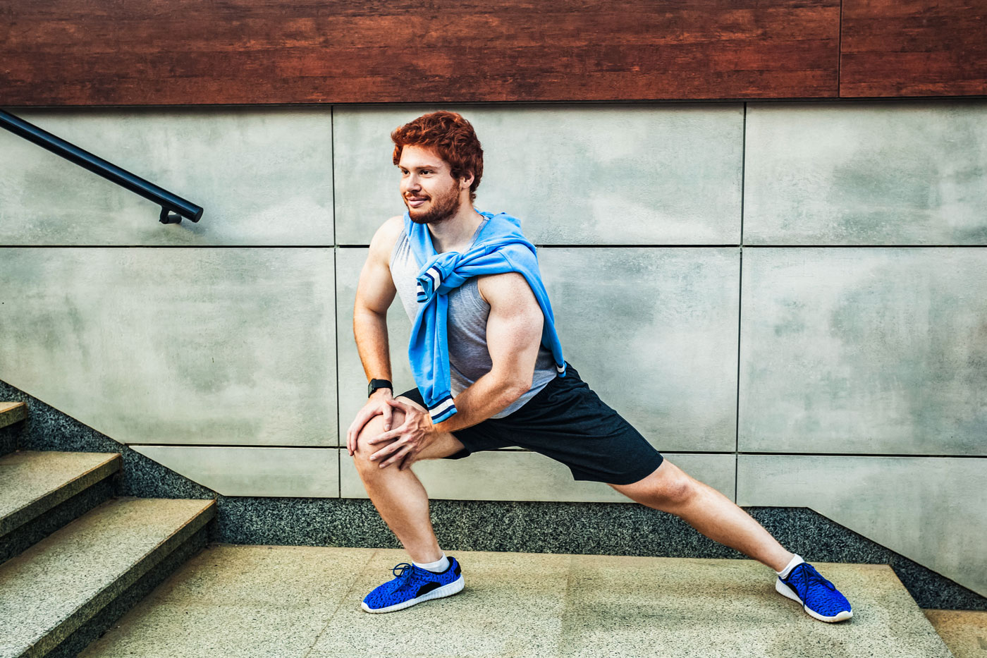 Junger Mann in Sportkleidung macht eine Dehn&uuml;bung auf einer Treppe zur F&ouml;rderung von Fitness, Stabilit&auml;t und innerer Kraft.