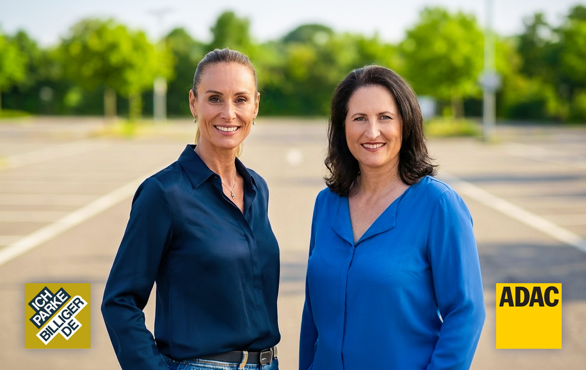 Zwei Frauen stehen nebeneinander auf einem Parkplatz im Freien. Beide lächeln in die Kamera. Im Hintergrund ist ein großer Parkplatz und Bäume zu sehen. Bei den Personen handelt es sich um Daniela Mursa, die Geschäftsführerin von ich-parke-billiger.de und Claudia Löffler, die Pressesprecherin des ADAC Berlin-Brandenburg e.V.