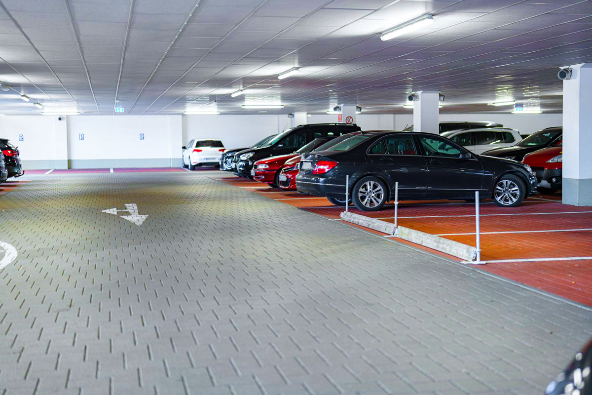 Parkhaus mit mehreren geparkten Autos und einem Pfeil auf dem Boden, der die Fahrtrichtung anzeigt